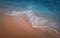 Serene blue sea with foamy waves hits the sandy shore. Beach and water texture, moody vertical background. Summer vacation seaside