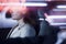 Serene businesswoman sitting in the car at night, illuminated and reflected lights on the car window