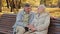 Serene caucasian older married couple rest sitting on bench in autumn park enjoy pleasant conversation outdoors man hugs