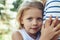 Serene cheerful girl embracing mom outdoors