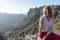 Serene Cute Tourist woman, laughing and admiring the freedom and the landscape in the mountain, sitting in a rock. Model sit and