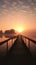 A serene dock leading to a beautiful sunset over a calm lake