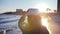 Serene Evening Promenade: Graceful Woman in a Stylish Hat Walking Along the Enchanting Waterfront at Sunset