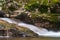 Serene Flowing River with Mossy Rocks and Stacked Stone Markers