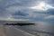 Serene image of the beach with sun poking through clouds