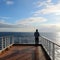 A serene image of a lone figure standing on the deck of a cruise ship