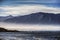 Serene image of mountain, ocean, light, and low clouds