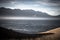 Serene image of mountain, ocean, light, and low clouds