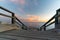 A Serene Journey to the Ocean: Horizontal View of a Wooden Staircase Leading to the Ocean, Capturing the Peaceful Moment of Sunset