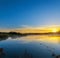 Serene lake at sunrise in forested, sun reflecting in the water with fog