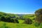 serene landscape with rolling hills, lush greenery and clear blue sky