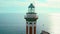 A serene lighthouse stands guard above the sea, basking in the warm glow of the sunset. Faro di Punta Carena in Capri