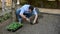 Serene male farmer planting seedlings of cucumbers in loosened black soil in the organic garden of his summer cottage