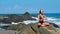 Serene meditation yoga. Brunette tourist woman meditating in lotus position on promontory above scenic Praia da Marinha