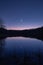 A serene, minimalistic moonlit night sky over a calm, reflective lake