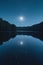 A serene, minimalistic moonlit night sky over a calm, reflective lake