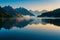 A serene mountain lake at dawn, with mist rising from the water