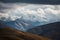 serene mountain range with clouds rolling above, and snow-capped peaks in the distance