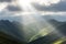 serene mountain range, with clouds and sunbeams filtering through the peaks