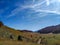 Serene mountainside view of untouched natural environment with mountains, hills and vast green grass field during autumn fall