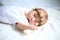 Serene newborn baby in the wreath lying on the white sheet