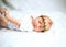 Serene newborn baby in the wreath lying on the white sheet