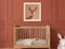 Serene nursery room with a framed fawn portrait above a wooden crib and a plush rabbit toy.