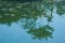 Serene reflections of a lush garden park, in the surface of a Thai lake.