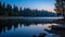 The serene scene of a lake at the blue hour and reflections of surrounding trees