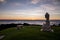 A serene statue of Buddha sitting on a shore of Pacific ocean watching sunset.