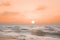 A serene summer beach with gentle waves under a soft peach fuzz color sunset. Modern trendy tone hue shade
