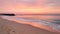 A serene sunset over a beach with soft pinks and oranges