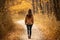 Serene unrecognizable woman walking on autumn forest path in nature, surrounded by woods