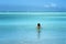 Serene vacation scene with back of woman in calm blue ocean waters.