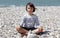 Serene yoga child breathing on a mineral pebble ocean beach