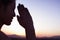 Serene young woman with eyes closed and hands together in prayer pose in the desert in China, focus on background