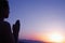 Serene young woman with hands together in prayer pose in the desert in China, silhouette, sun setting