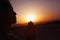 Serene young woman with hands together in prayer pose in the desert in China, silhouette, sun setting