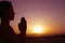 Serene young woman with hands together in prayer pose in the desert in China, silhouette, sun setting, profile