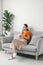 Serene young woman resting on sofa wearing casual home clothes wireless headphones enjoy weekend free time