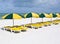 Series of colorful lounge chairs on a white sand