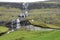 Series of waterfalls splash behind the stone house with roof covered by grass.