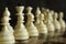 Series of white chess figures focused and unfocused on wooden chessboard as strategy game concept.