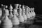 Series of white chess figures focused and unfocused on wooden chessboard as strategy game concept black and white monochrome.