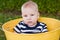 Serious 7-month-old baby in yellow bucket