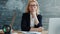 Serious adult woman sitting at desk in university classroom looking at camera