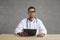 Serious African American doctor looking at camera sitting at desk studio shot