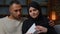 Serious African Latina man husband with arabian muslim woman wife opening envelope paper letter upset couple multiracial