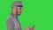 Serious arabic casual man using smartphone while walking on a green screen, chroma key.