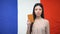 Serious Asian female showing passport against French flag background, embassy